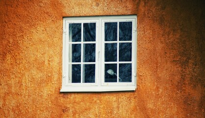 Closeup shot of a white house window on an orange wall