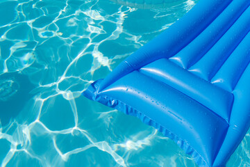 Bright blue summer pool lounger float on a rippled swimming pool
