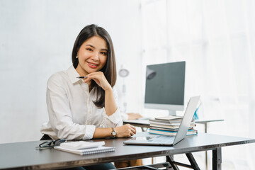 Young Attractive Asian business female finance worker sitting at work, answering e-mails on the...