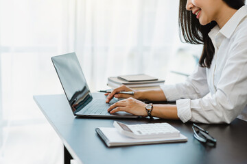 Young Attractive Asian business female finance worker sitting at work, answering e-mails on the tablet.