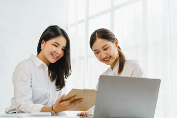 Obraz premium two friends of business female people using a computer while working together in the office, hands pointing to clipboard.