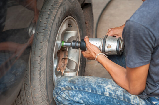 The mechanic uses a tool to remove the nuts from the wheels of a car.