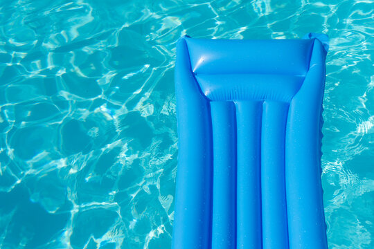 Bright blue summer pool lounger float on a rippled swimming pool