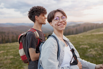 Portrait of cheerful happy woman hiking with male friend or boyfriend by mountains.