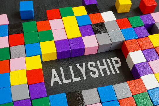 Word allyship and colorful cubes on the dark surface.