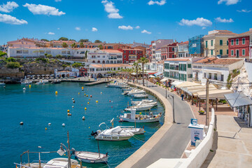View of colourful cafes, restaurants and boats in harbour against blue sky, Cales Fonts, Menorca, Balearic Islands, Spain