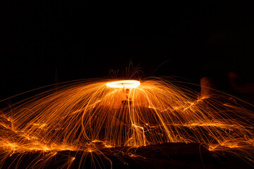 Lighting from spinning steel wool on a stone near the sea of Steel Wool Photography.