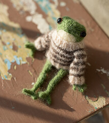 Knitted frog - a toy sits on the boards