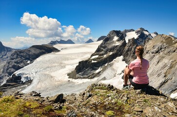 Naklejka na ściany i meble young woman enjoying the view over the mountains and the glacier. Magical moment to enjoy. Swiss Alps.High quality photo