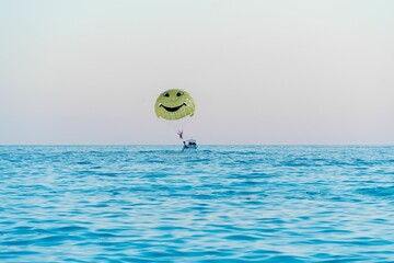 Green parachute with a smiley face and a boat in the sea