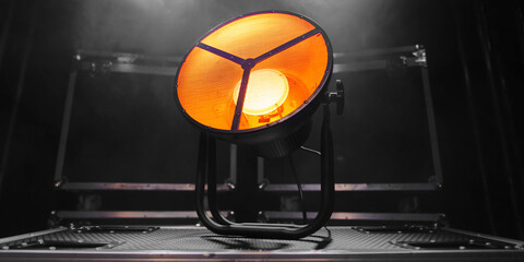 A round stage lighting device stands on boxes with equipment