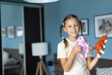 a girl of eight years old plays with knitted toys