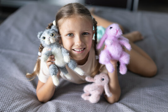 a girl of eight years old plays with knitted toys