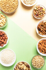 Frame of set of bowls with cereals and nuts on two-tone beige-green backdrop. Top view. Close up.