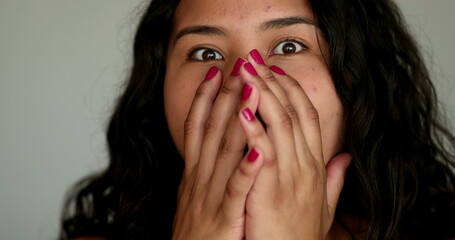 Hispanic girl shock surprise reaction covering mouth with hands