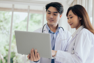 Asian two male female professional doctor using computer laptop checking patient's medical records...