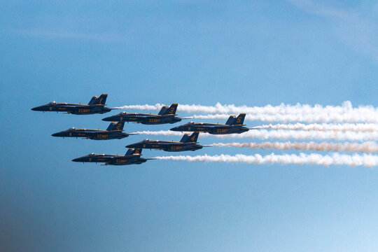 Six US Navy Blue Angel jets flying in formation leaving a vapor trail