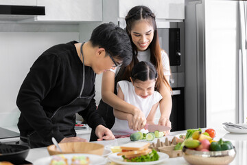 Asian girl learning to cook with mom and dad. Do activities together with your family in a fun and joyful way. There is a father and mother taking care of them closely.