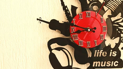 Fotobehang Closeup of a red vinyl clock with musical instruments and 'life is music' on beige wall background © Cn/Wirestock Creators