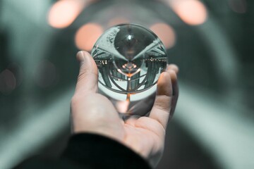 Human hand holding orb with reflection isolated in blurred background