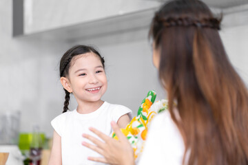 Asian girl learning to cook with mom Do activities together with your family in a fun and joyful way. There is a mother taking care of them closely.