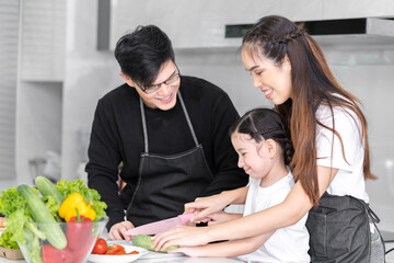 Asian girl learning to cook with mom and dad. Do activities together with your family in a fun and joyful way. There is a father and mother taking care of them closely.