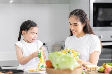Asian girl learning to cook with mom Do activities together with your family in a fun and joyful way. There is a mother taking care of them closely.