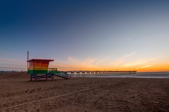 Scenic Sunset In Los Angeles Beach With Rainbow Colored Lifeguard Tower Symbolizing Pride.