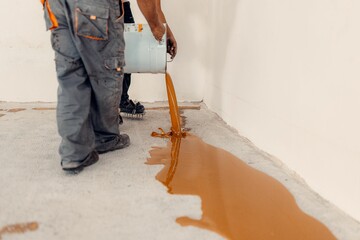 Worker applying a yellow epoxy resin bucket on floor