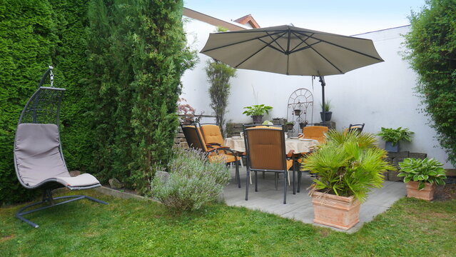 gem&uuml;tliche Gartenterrasse inmitten von diversen Pflanzen und Blumen