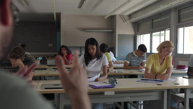 Young teacher giving a presentation in high school classroom. Profesor speaking to a group of teenage people. Education, college and youth concept. Slow motion high quality 4k footage