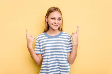 Young caucasian girl isolated on yellow background indicates with both fore fingers up showing a blank space.