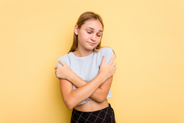 Young caucasian girl isolated on yellow background hugs, smiling carefree and happy.