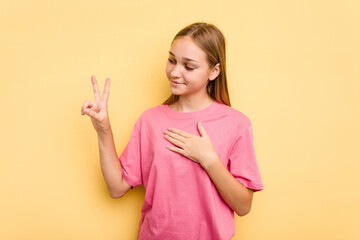 Young caucasian girl isolated on yellow background taking an oath, putting hand on chest.