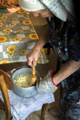 Fototapeta na wymiar Old grandmother cooking ground potatoes
