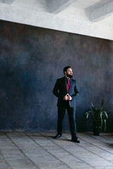 Portrait of attractive young bearded man in suit on dark background