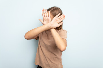 Young caucasian girl isolated on blue background keeping two arms crossed, denial concept.