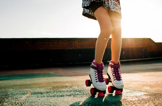 Childs legs with roller boots in in a sequin dress dancing at sunset