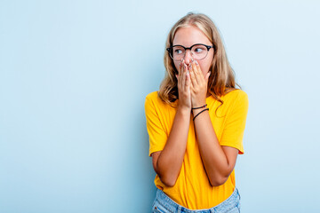 Caucasian teen girl isolated on blue background thoughtful looking to a copy space covering mouth...