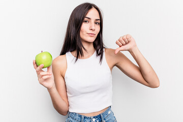 Young caucasian woman holding an apple isolated on white background showing a dislike gesture,...