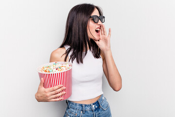 Young caucasian woman eating popcorn isolated on white background shouting and holding palm near opened mouth.