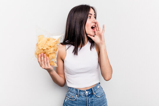 Young Caucasian Woman Holding A Bag Of Chips Isolated On White Background Shouting And Holding Palm Near Opened Mouth.