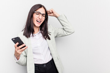 Young business caucasian woman holding mobile phone isolated on white background raising fist after a victory, winner concept.