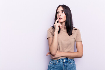 Young caucasian woman isolated on pink background looking sideways with doubtful and skeptical expression.