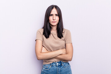 Young caucasian woman isolated on pink background frowning face in displeasure, keeps arms folded.