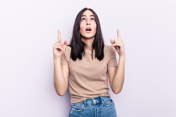 Young caucasian woman isolated on pink background pointing upside with opened mouth.