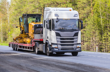 Truck transports road equipment on road.