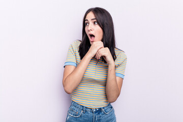 Young caucasian woman isolated on pink background praying for luck, amazed and opening mouth looking to front.