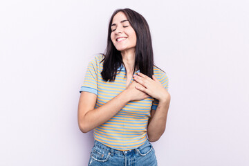 Young caucasian woman isolated on pink background laughing keeping hands on heart, concept of happiness.