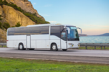 Tourist bus moves along the mountains on the sea - obrazy, fototapety, plakaty